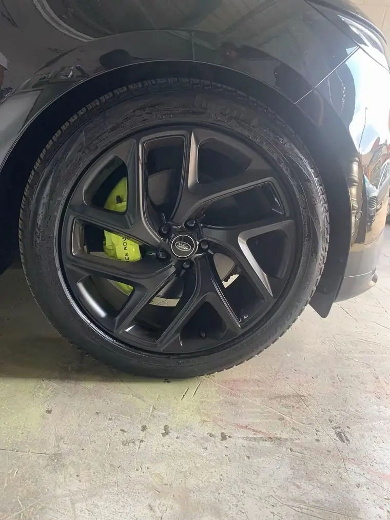Lime green calliper seen through the spokes of a black Range Rover wheel
